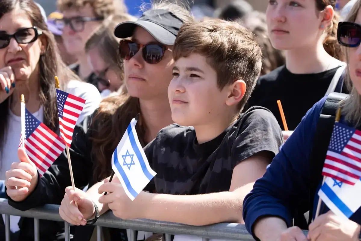 A crowd waving Israeli flags at a rally, expressing solidarity with Israel and the values supported by CJP giving in Boston.