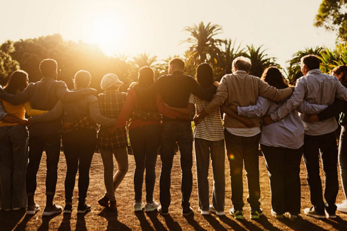 Back view of people of all ages standing arm in arm at sunset, reflecting Jewish community impact in Boston and the collective Jewish philanthropic impact in Boston.