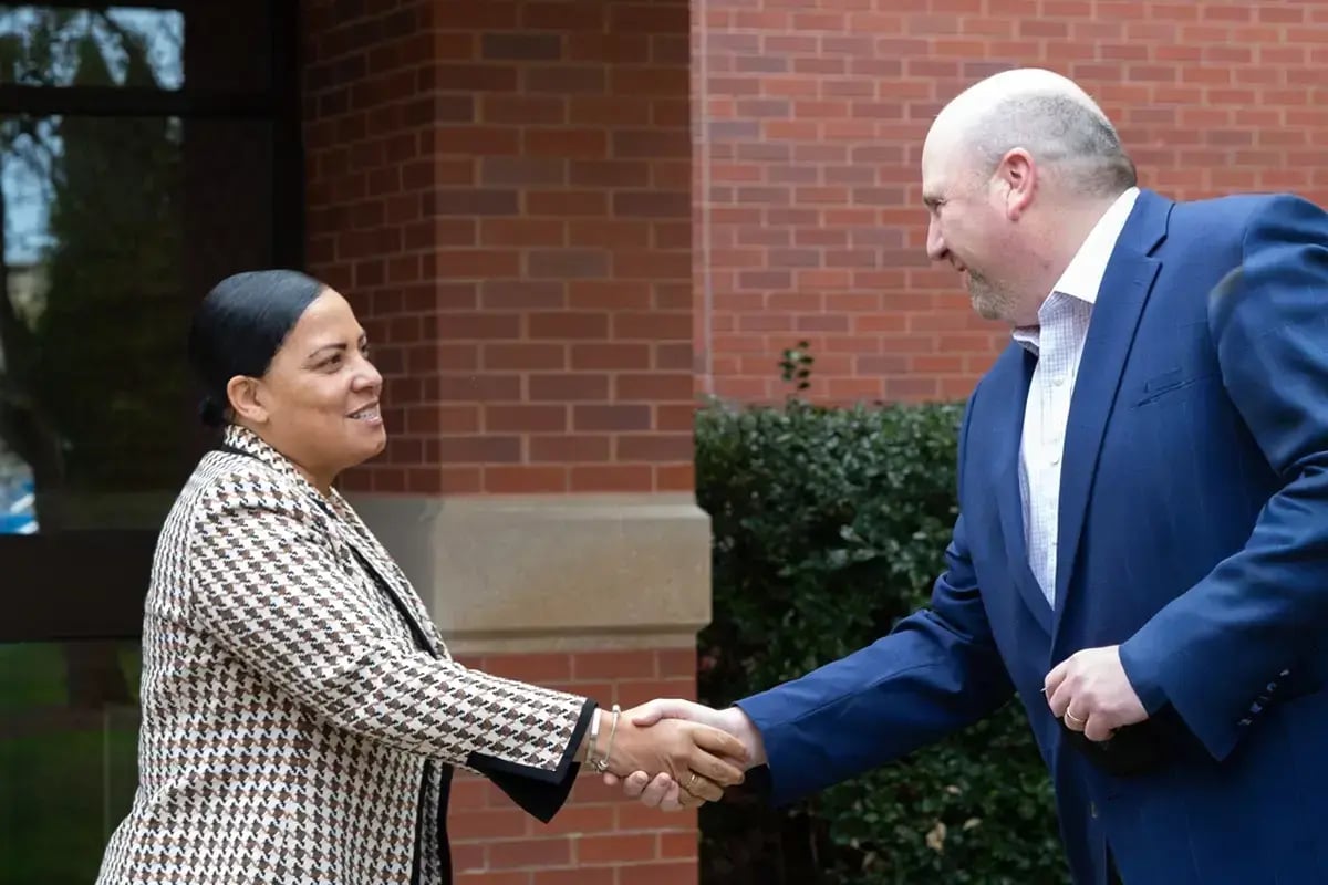 Professionally dressed woman and man shaking hands, representing organizations strengthened by CJP security grants in the Boston Jewish community.