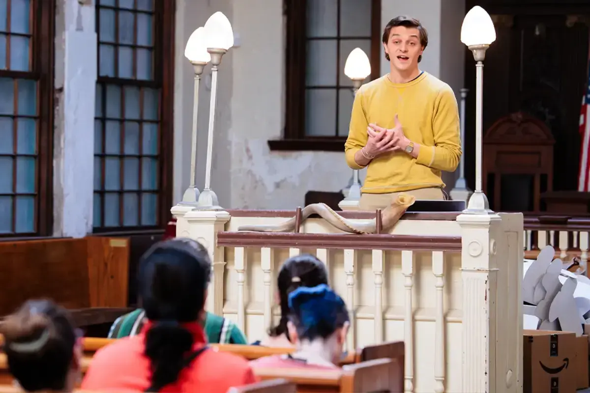 Young man talking to families inside a synagogue, showcasing welcoming Jewish communities and parenting resources in Boston.