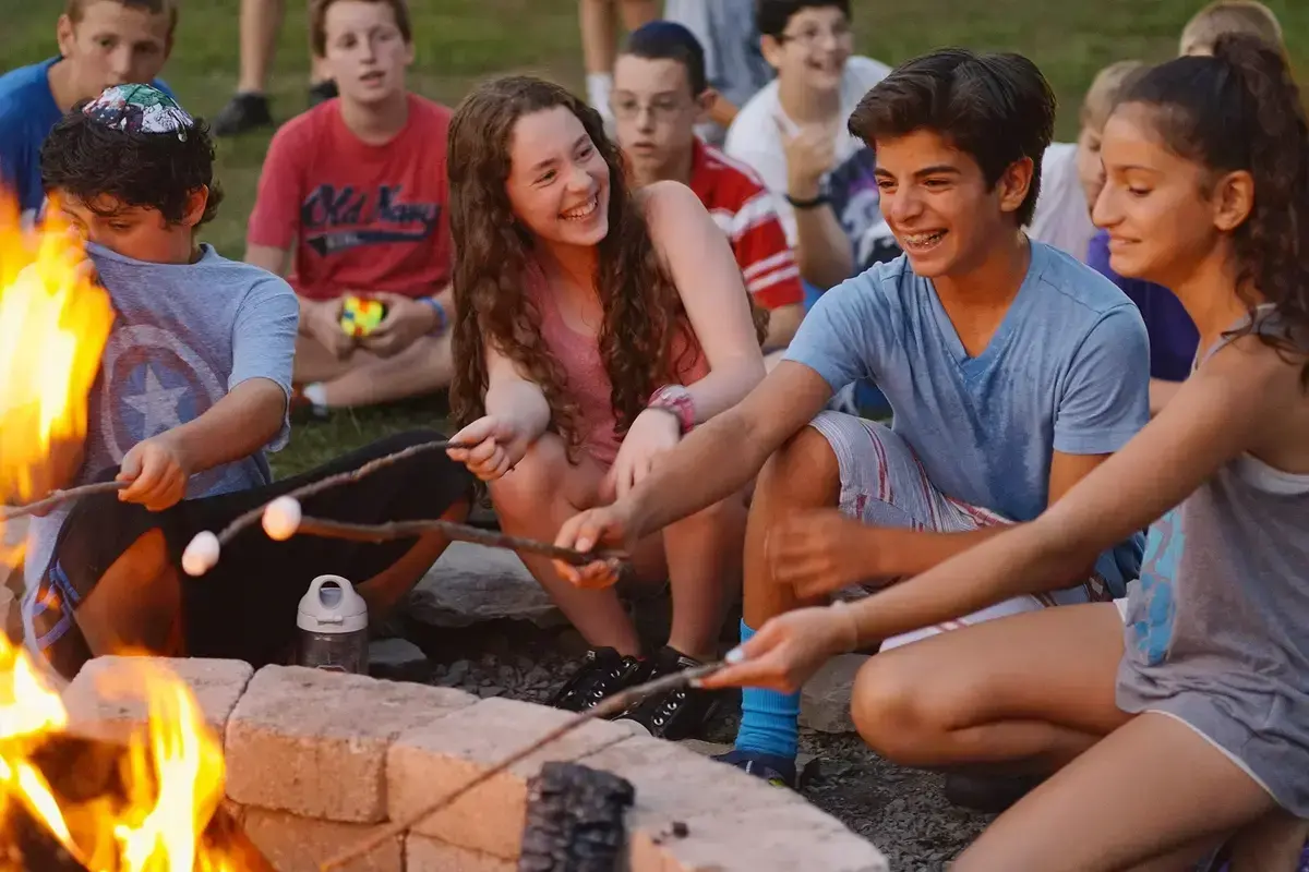 Jewish summer camp teens roasting marshmallows together around a campfire. Jewish summer camp teens roasting marshmallows together around a campfire.