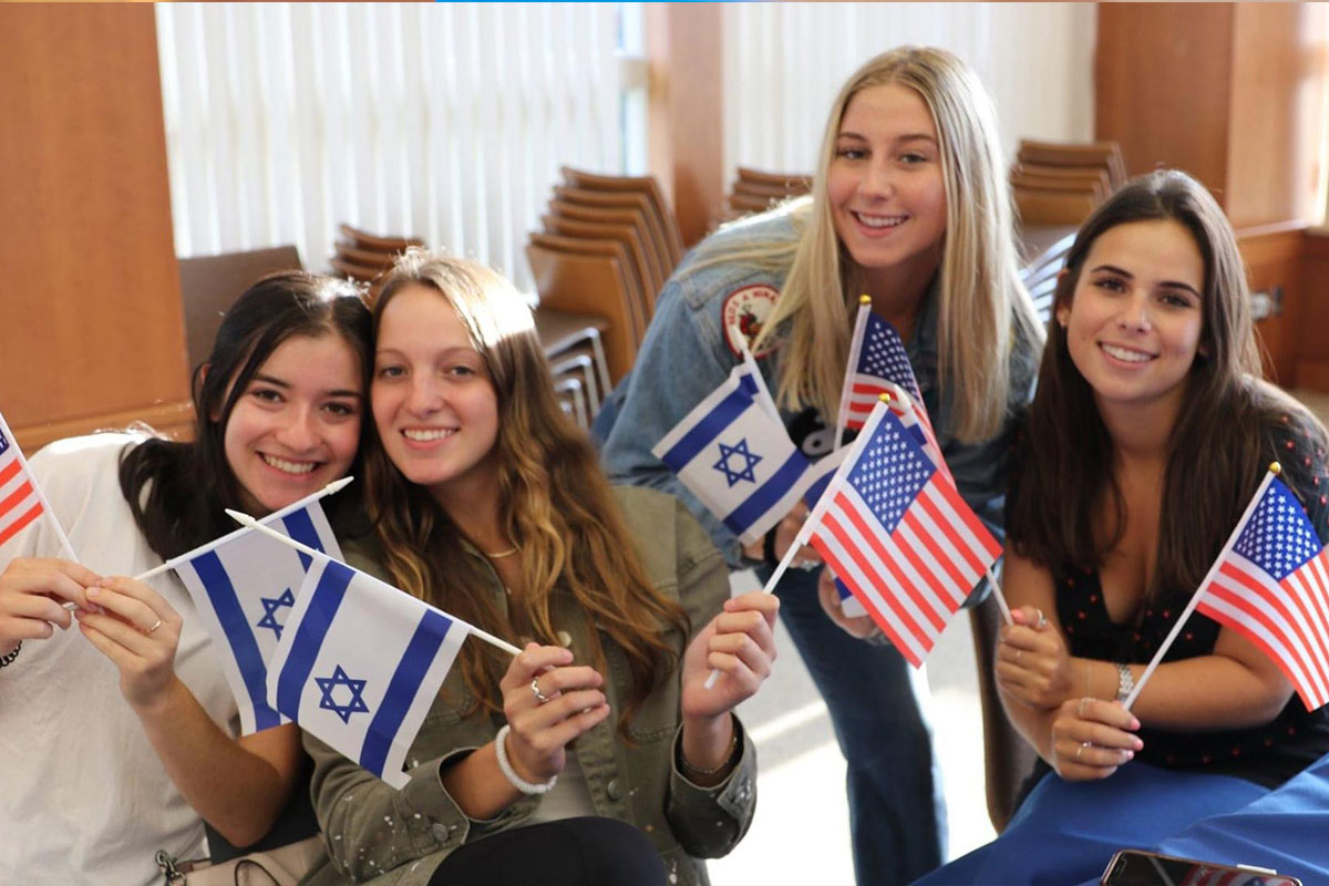 Jewish life Boston campus initiatives with college students holding Israeli and American flags, celebrating Jewish identity and community on campus in Greater Boston.