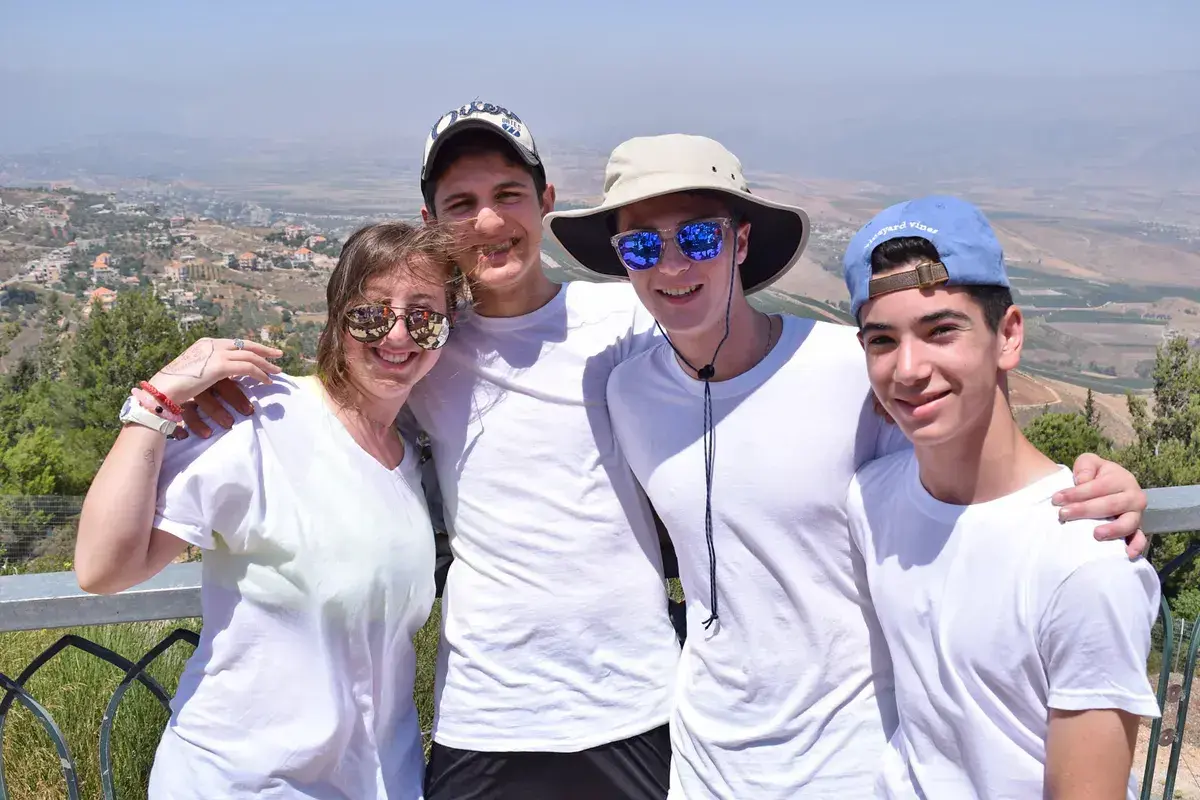 Israel teen travel boston: group of teens smiling together at a scenic overlook in Israel, capturing friendship and shared travel experiences with panoramic landscape views.